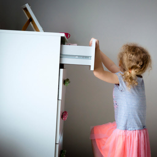 child pulling on top drawer of a dresser that is tipping over