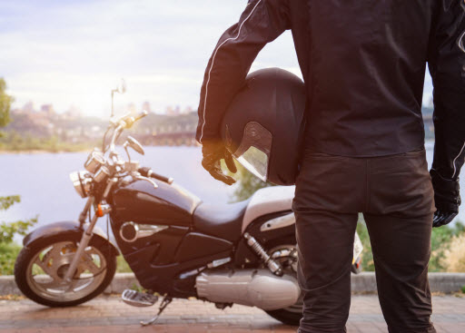motorcyclist holding helmet while standing next to their motorcycle