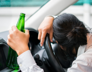 driver asleep at the wheel with a beer bottle in hand