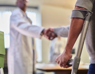 patient in crutches shaking doctors hand