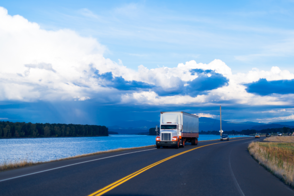 white semi-truck driving near lake