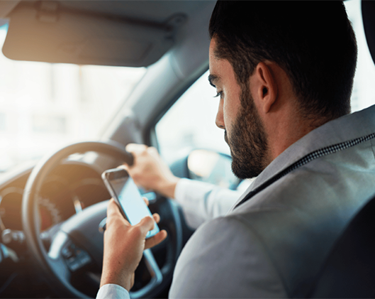 a man pressing his phone while driving