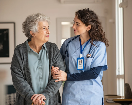 a female nurse holding an elderly lady while she walks