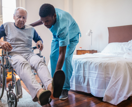 a male nurse helping an elderly man wear his slippers